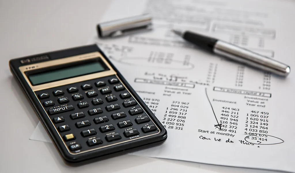 Image of a person reviewing financial charts and planning with calculator and laptop.