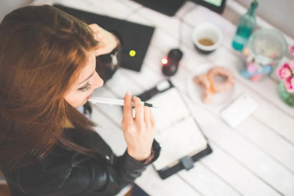 Focused person working at a clean desk with a planner and laptop.
